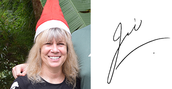 A close-up headshot of Animals Asia’s Founder and CEO, Jill Robinson smiling into the camera with blonde shoulder-length hair. She’s wearing a black t-shirt with the white Animals Asia logo on her shirt sleeve and a red and white Father Christmas hat.